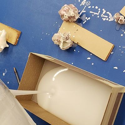 Liquid acrylic resins being poured into a trophy mold in order to cast sea shells.